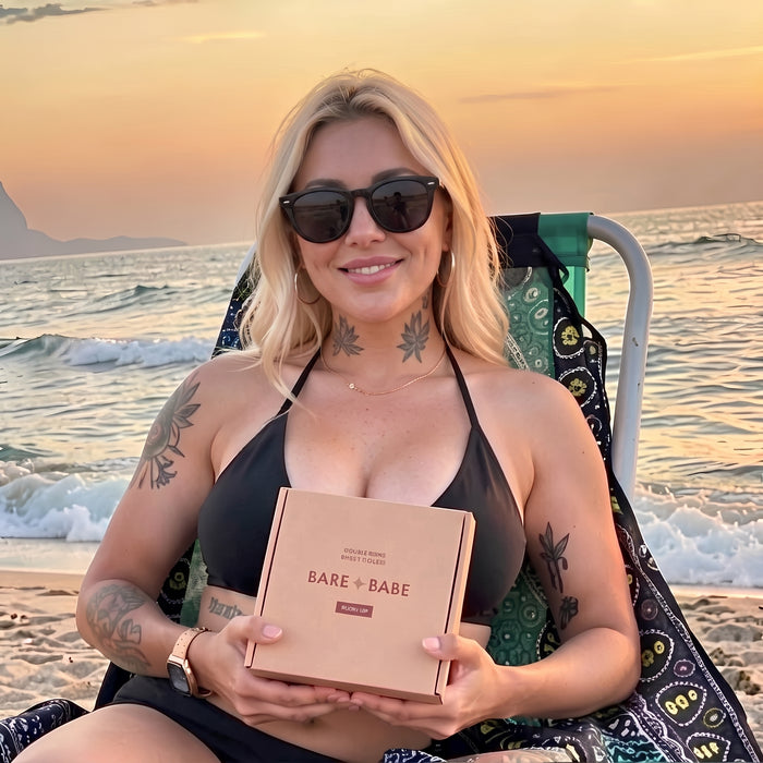 Woman in sunglasses and a black halter top sitting in a beach chair at sunset, holding a box of Extra-Boost Sticky Push Up Inserts, a customer review photo