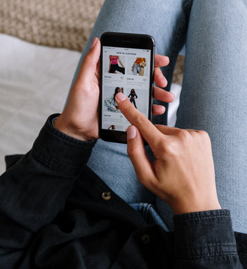 Hands scrolling a clothing shop app on a smartphone, for a guide to finding the best nipple covers near you or buying reusable silicone nipple covers online