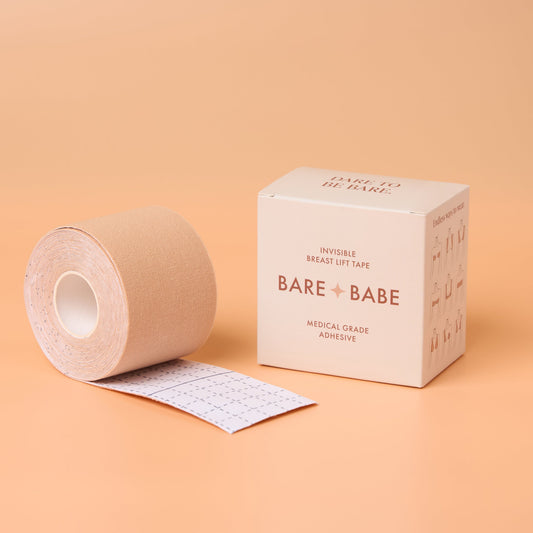Boob Tape Kit in Creme: a roll of breast lift tape partly unrolled to show the cutting-grid backing, beside its Dare to Be Bare box marked invisible breast lift tape with medical-grade adhesive.