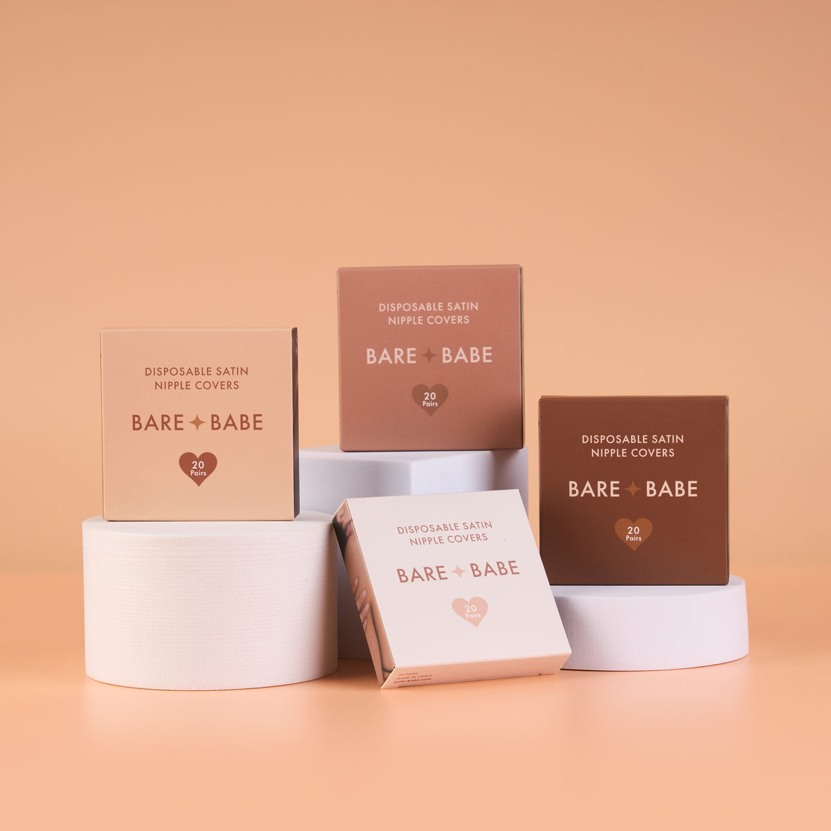 Satin Nipple Pasties boxes in four shades scattered with round and flower-shaped disposable nipple covers, 20 pairs per box, soft satin with a hypoallergenic, medical-grade adhesive.