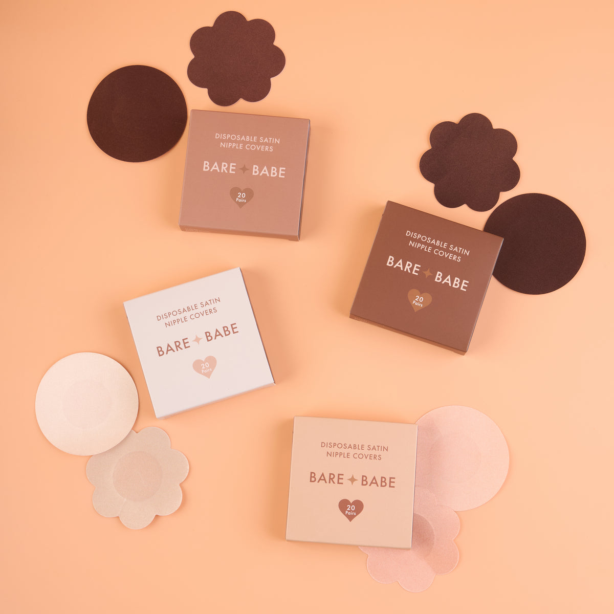 Close-up of Satin Nipple Pasties boxes labeled disposable satin nipple covers, 20 pairs, in four shades, with round and flower nipple pasties spread around them.