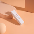 Invisible Lingerie Tape box resting on peach display props, a slim pack of pre-cut double-sided clothing tape strips marked secure fit all day long and gentle for all skin types.