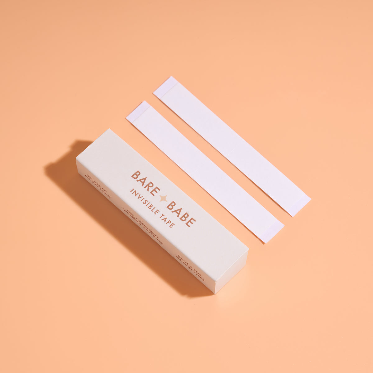 Invisible Lingerie Tape box with two pre-cut double-sided tape strips, clear fashion tape for securing plunging necklines, wrap tops and straps to skin.