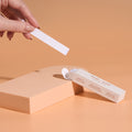 Invisible Lingerie Tape: a hand lifts one strip from the open box, pre-cut double-sided clothing tape that keeps necklines and straps in place.