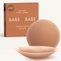 Adhesive Nipple Covers in Caramel: a pair of round, matte, reusable silicone nipple covers, one tilted to show the sticky side, in front of the Caramel box marked Sticky and medical-grade silicone.