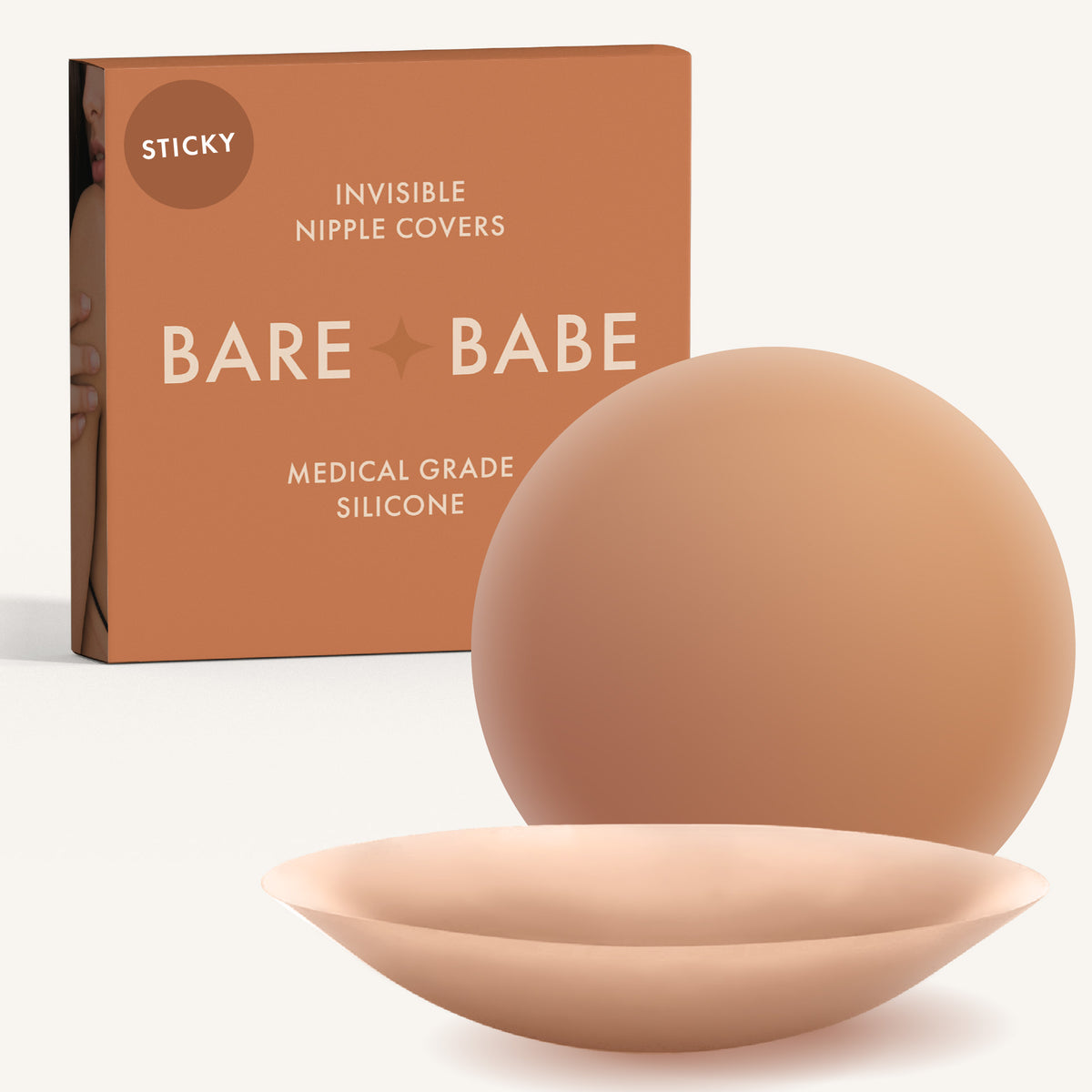 Adhesive Nipple Covers in Caramel: a pair of round, matte, reusable silicone nipple covers, one tilted to show the sticky side, in front of the Caramel box marked Sticky and medical-grade silicone.