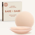 Adhesive Nipple Covers in Creme: a pair of round, matte, reusable silicone nipple covers, one tilted to show the sticky side, in front of the Creme box marked Sticky and medical-grade silicone.