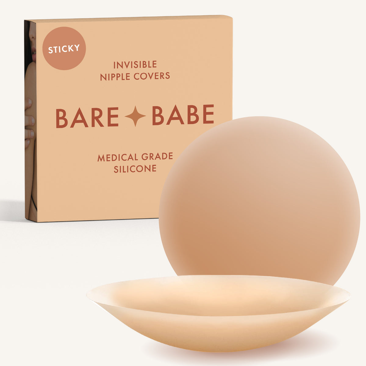 Adhesive Nipple Covers in Honey: a pair of round, matte, reusable silicone nipple covers, one tilted to show the sticky side, in front of the Honey box marked Sticky and medical-grade silicone.