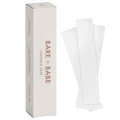 Invisible Lingerie Tape box standing upright beside clear pre-cut strips of double-sided tape for clothes and body, 50 strips per pack.
