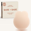 Lifting Nipple Covers (Two-Tabs) in Creme: two-tab reusable silicone lift nipple cover in front of its Creme Bare Babe box, labelled Lifting, invisible nipple covers, medical grade silicone