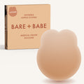 Lifting Nipple Covers (Two-Tabs) in Honey: two-tab reusable silicone lift nipple cover in front of its Honey Bare Babe box, labelled Lifting, invisible nipple covers, medical grade silicone