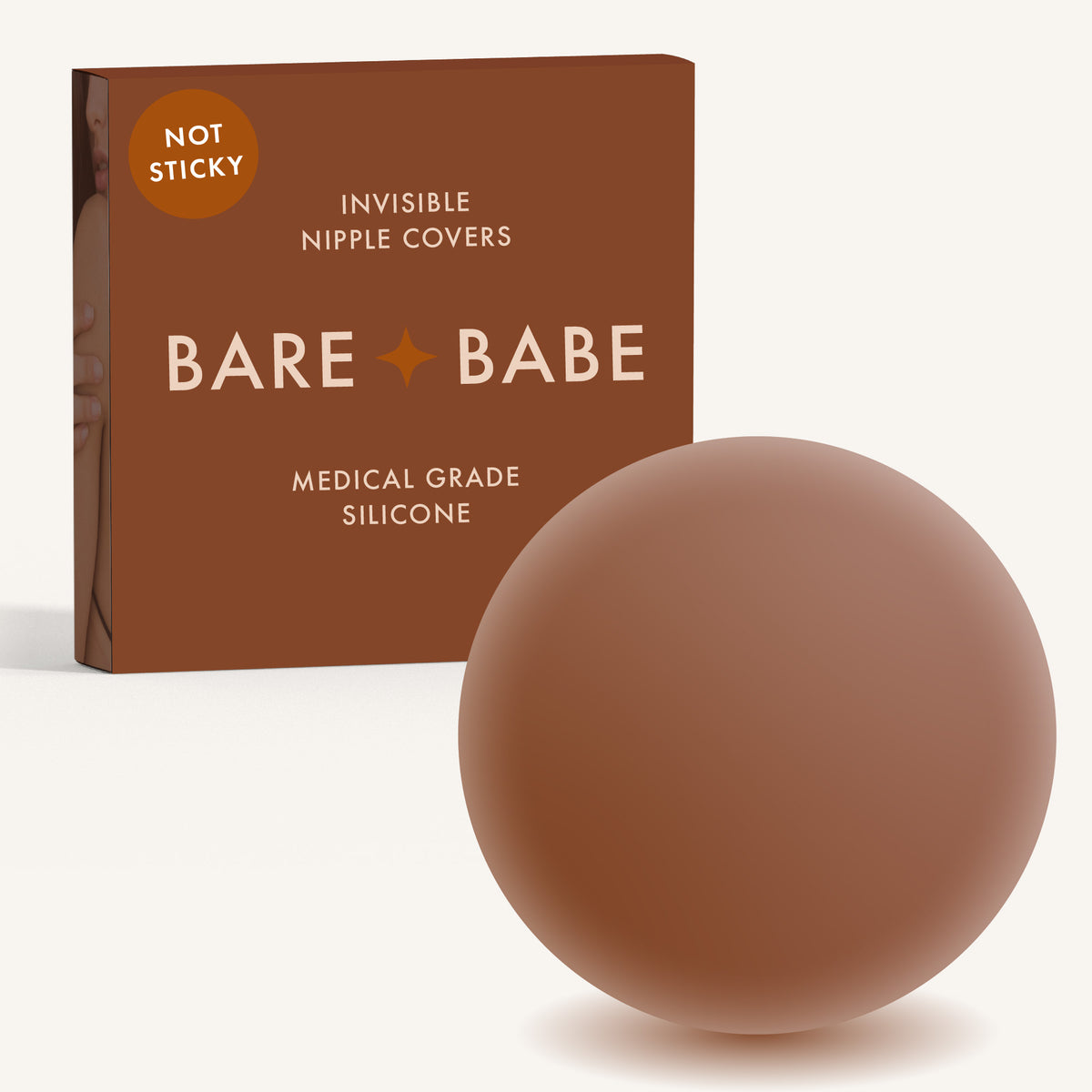 Non-Adhesive Nipple Covers in Cocoa: a round, matte, grippy silicone nipple cover in front of the Cocoa Bare Babe box marked Not Sticky and medical-grade silicone, reusable with no adhesive.