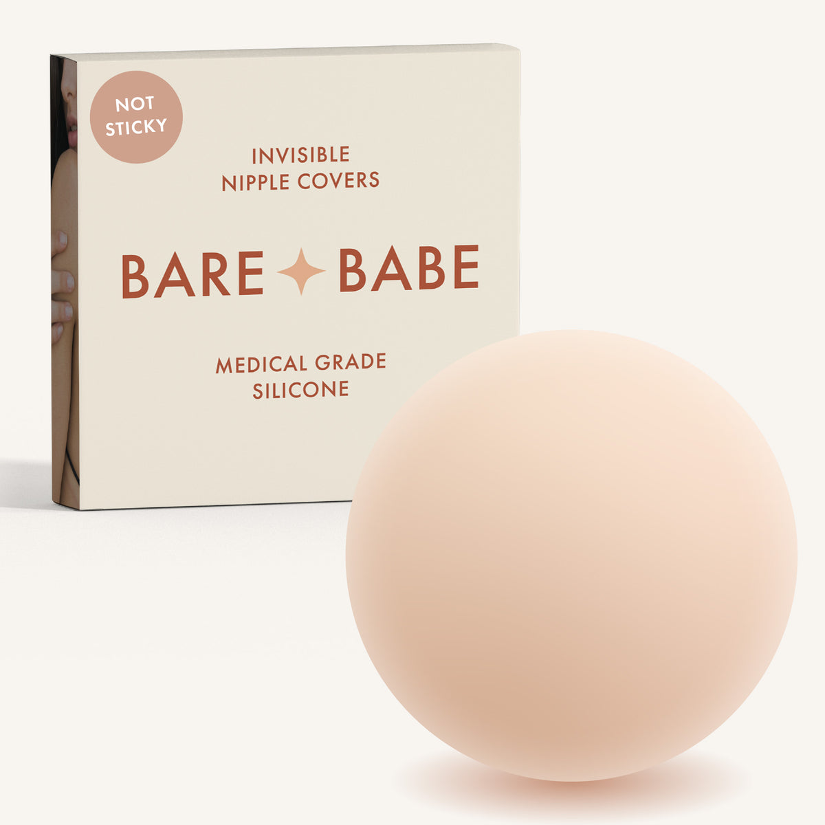 Non-Adhesive Nipple Covers in Creme: a round, matte, grippy silicone nipple cover in front of the Creme Bare Babe box marked Not Sticky and medical-grade silicone, reusable with no adhesive.