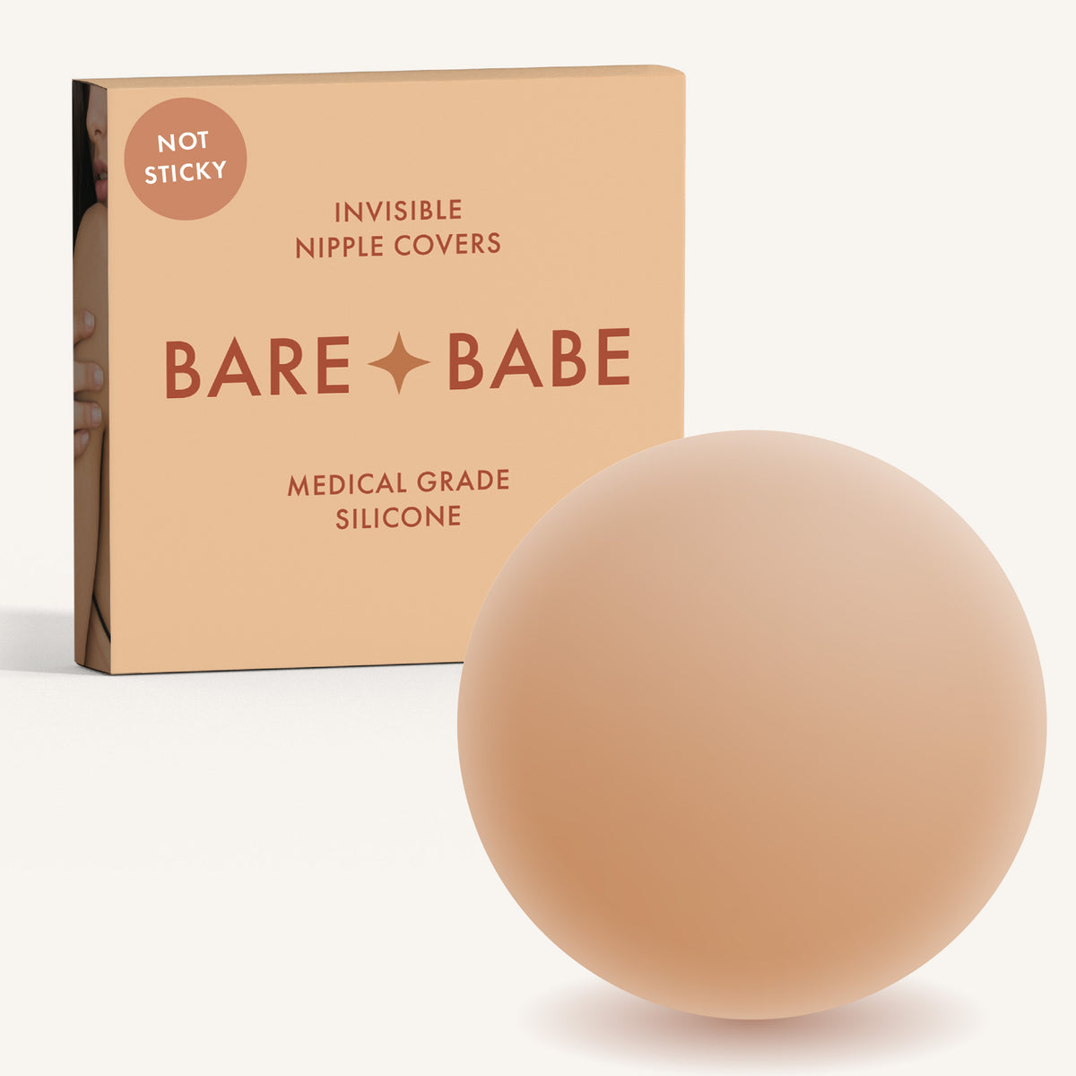 Non-Adhesive Nipple Covers in Honey: a round, matte, grippy silicone nipple cover in front of the Honey Bare Babe box marked Not Sticky and medical-grade silicone, reusable with no adhesive.