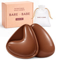 Extra-Boost Sticky Push Up Inserts in Cocoa, a pair of double-sided sticky push-up bra inserts in front of the Bare Babe Push Up box and white drawstring travel bag