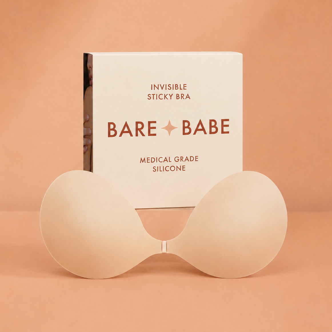 Silicone Sticky Bra in Creme, a strapless, backless adhesive bra with a front clasp, standing in front of its Bare Babe box labeled Invisible Sticky Bra, medical grade silicone
